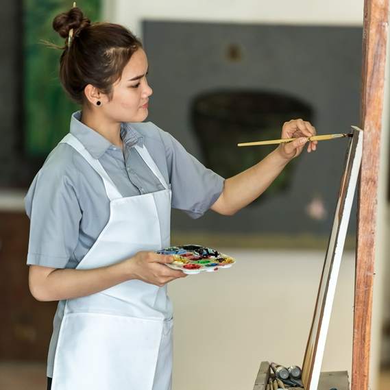 artist wearing a protective apron whilst at the easel 