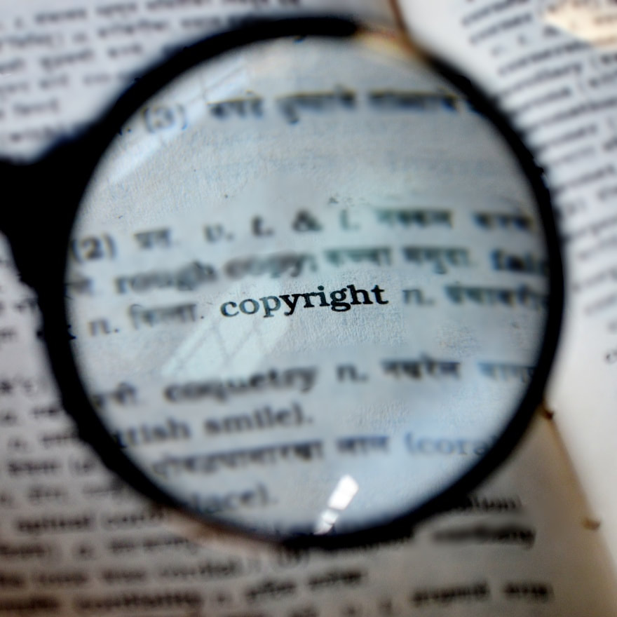Magnifying glass over a book with the word 'Copyright' magnified