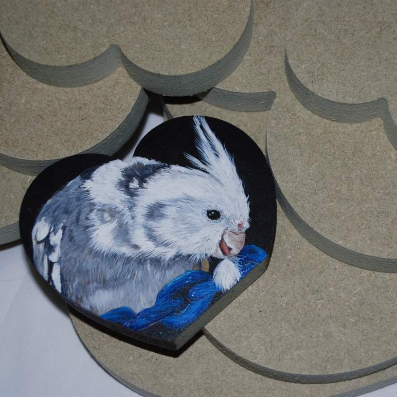 MDF hearts and a white faced cockatiel painted in acrylics