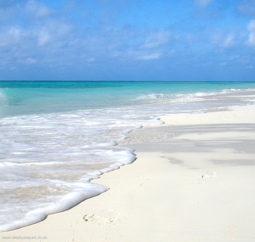 A beautiful tropical beach of pale golden sand, azure water and light blue skies