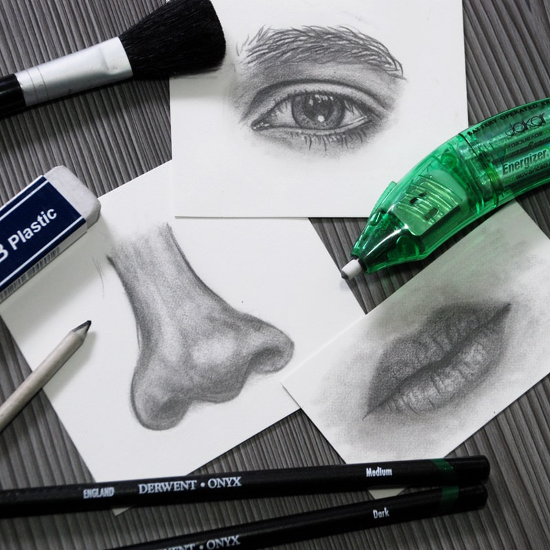 Graphite pencil drawings of eyes, nose and lips plus art tools